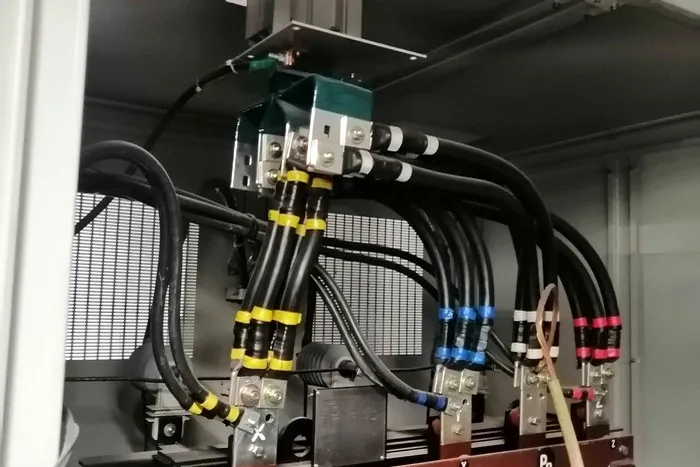 Conexiones de potencia normalizadas y marcadas por fase dentro de un tablero.